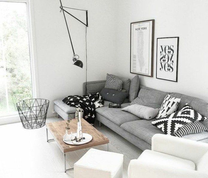 ein graues Sofa weiße Bilder weißer Sessel Couchtisch aus Holz .